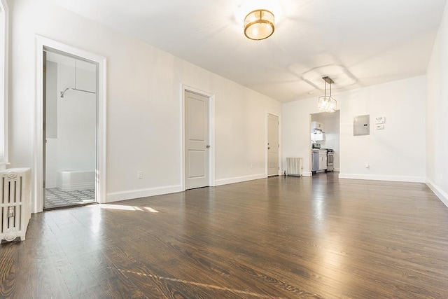 unfurnished living room featuring dark hardwood / wood-style flooring, radiator heating unit, and electric panel