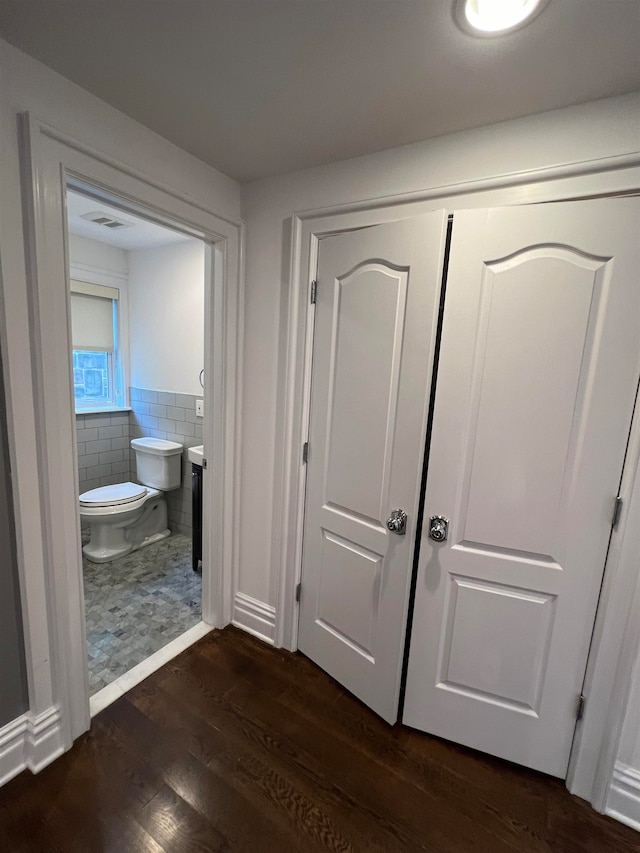 corridor with dark hardwood / wood-style flooring and tile walls