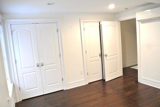 unfurnished bedroom with dark hardwood / wood-style flooring and two closets