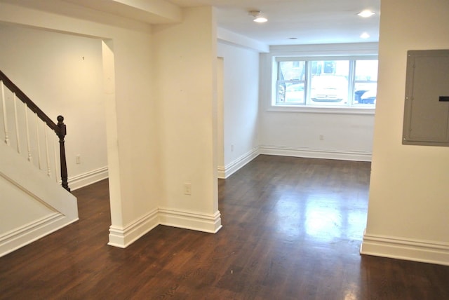 spare room featuring electric panel and dark hardwood / wood-style floors