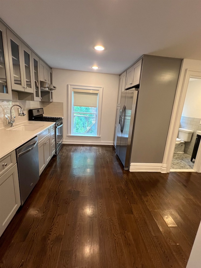 kitchen featuring dark wood-type flooring, decorative backsplash, sink, and stainless steel appliances