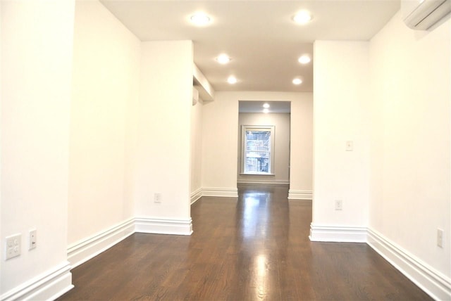 spare room with a wall unit AC and dark hardwood / wood-style flooring