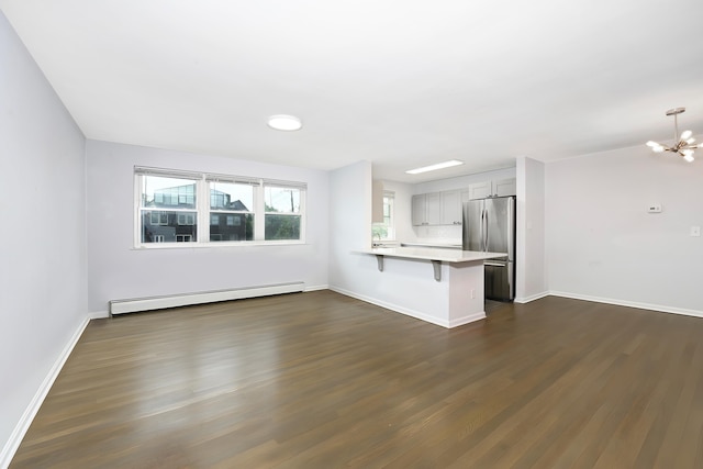 unfurnished living room featuring baseboards, dark wood-style flooring, a notable chandelier, and baseboard heating