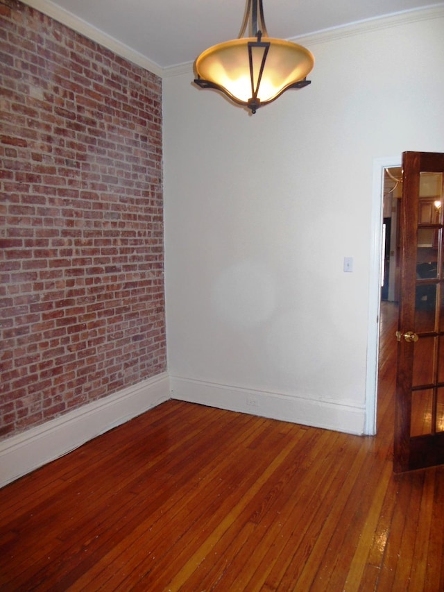 spare room with crown molding, brick wall, and hardwood / wood-style flooring