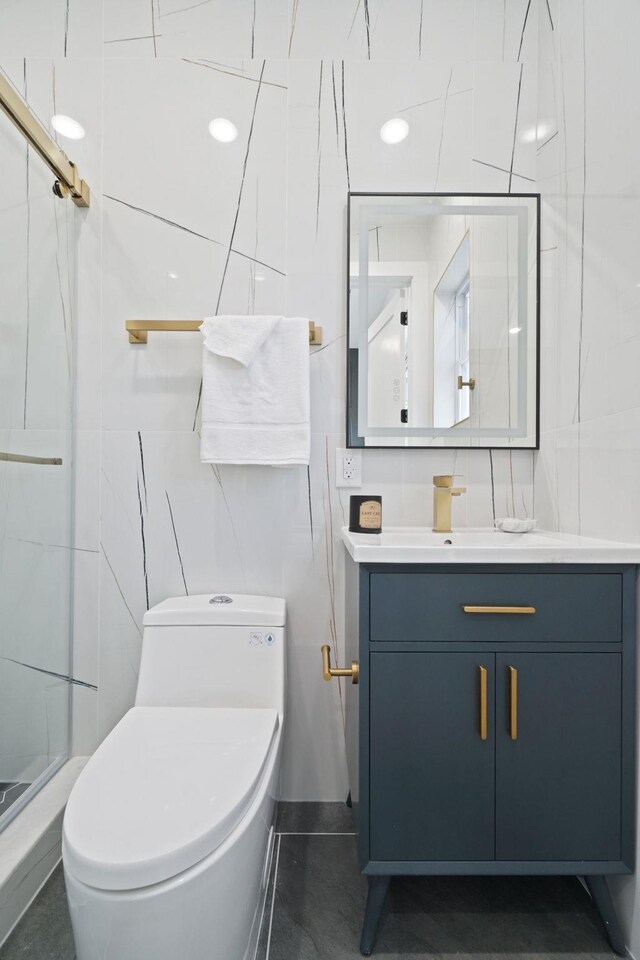 bathroom with tile walls, a shower with shower door, vanity, and toilet