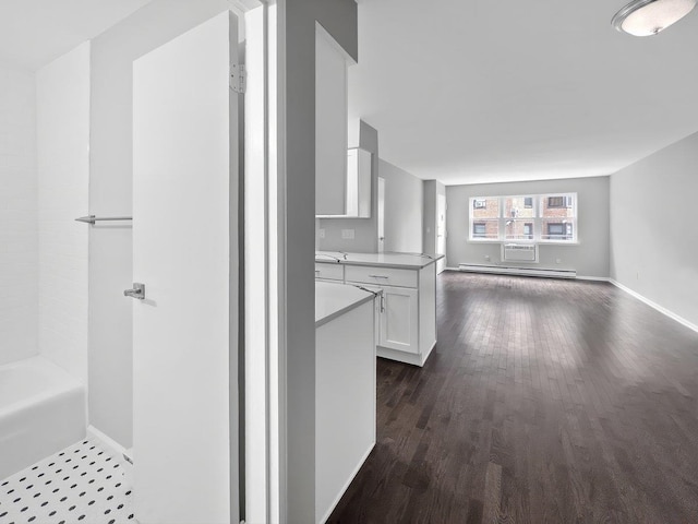 interior space with dark wood-style flooring, a baseboard radiator, light countertops, open floor plan, and white cabinets