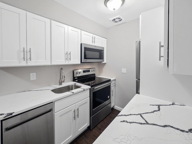 kitchen with visible vents, dark wood-type flooring, stainless steel appliances, white cabinetry, and a sink