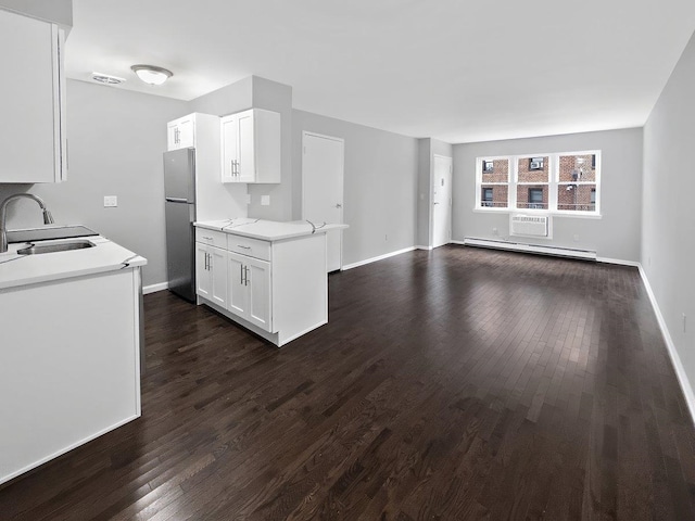 kitchen with a baseboard radiator, dark wood-type flooring, freestanding refrigerator, light countertops, and a sink