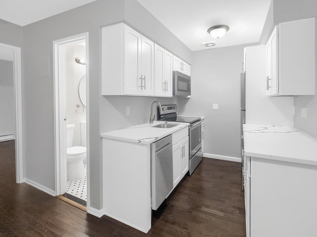 kitchen with dark wood-style flooring, stainless steel appliances, a sink, and light countertops