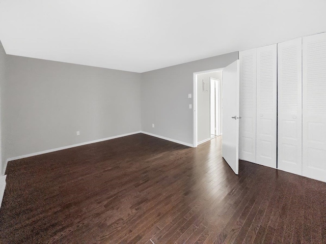 unfurnished bedroom with dark wood-type flooring and baseboards