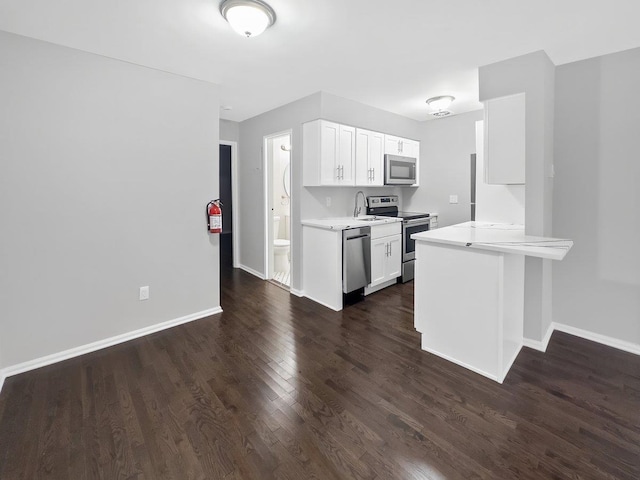 kitchen with dark wood-style floors, stainless steel appliances, light countertops, a sink, and baseboards