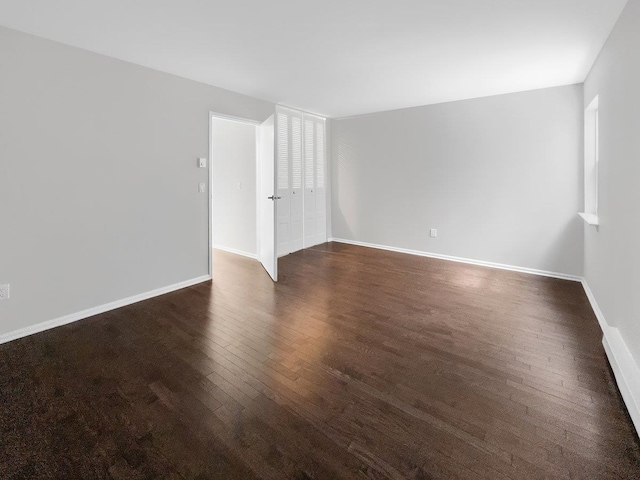 spare room with dark wood-style floors and baseboards