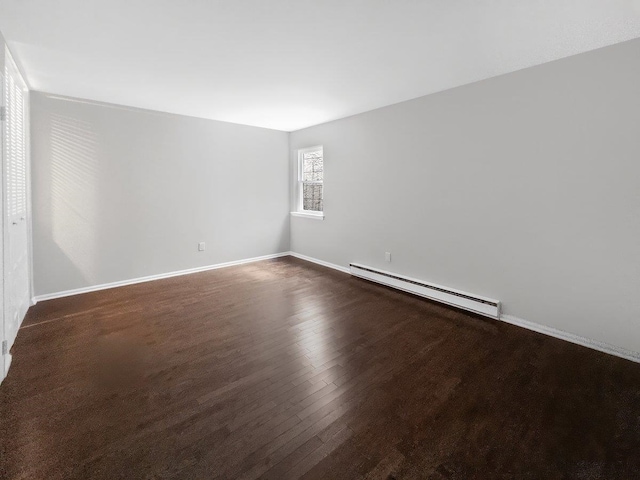 empty room with baseboards, baseboard heating, and wood finished floors