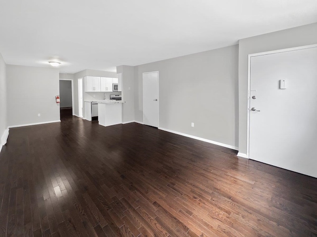 unfurnished living room featuring baseboards and dark wood finished floors