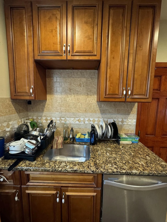 kitchen featuring dishwasher, dark stone countertops, decorative backsplash, and sink