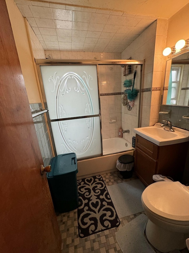 full bathroom with vanity, toilet, combined bath / shower with glass door, and tile walls