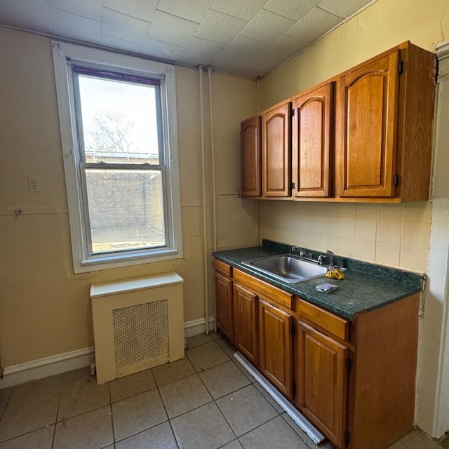 kitchen featuring light tile patterned flooring, radiator heating unit, and sink