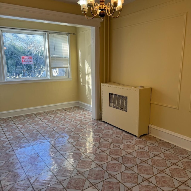 tiled spare room with a chandelier