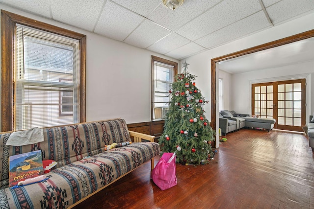 living room featuring french doors, wood walls, hardwood / wood-style flooring, and a drop ceiling