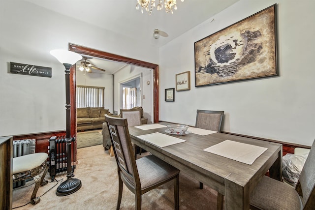 dining space with ceiling fan with notable chandelier and light carpet