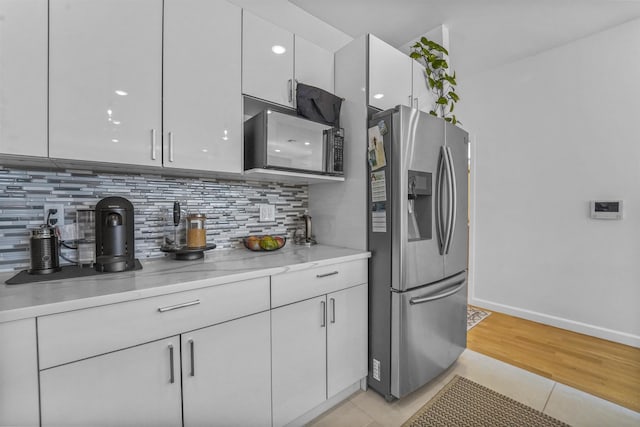 936 Pavonia Ave # 3A, Jersey City, NJ 07306 - kitchen featuring backsplash, baseboards, white cabinets, and stainless steel fridge with ice dispenser