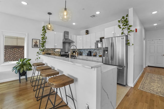 936 Pavonia Ave # 3A, Jersey City, NJ 07306 - kitchen featuring wall chimney range hood, a breakfast bar, visible vents, stainless steel appliances, and a peninsula