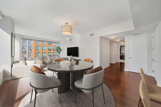 dining space with wood-type flooring and baseboards