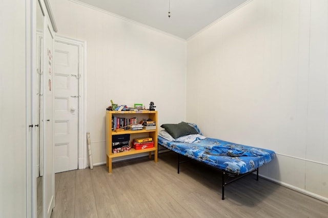bedroom with baseboards, ornamental molding, and light wood-style flooring