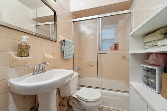 bathroom with bath / shower combo with glass door, backsplash, toilet, and tile walls