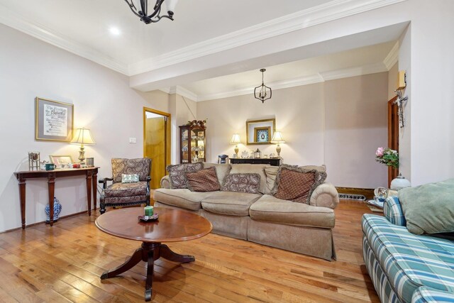 living area with crown molding, baseboards, an inviting chandelier, and hardwood / wood-style floors