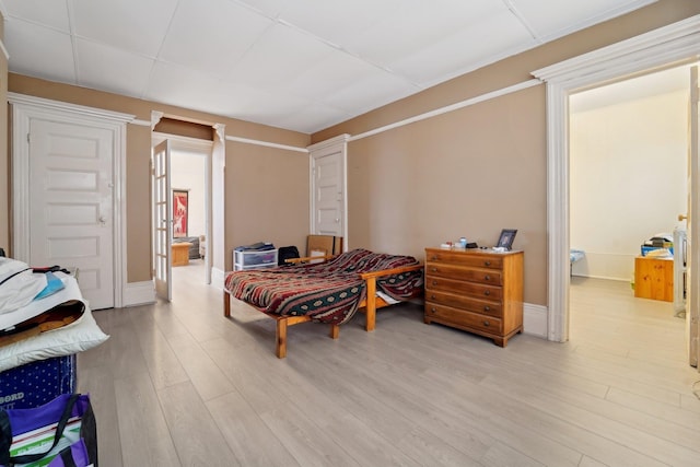 bedroom featuring light wood-style floors, baseboards, and a paneled ceiling