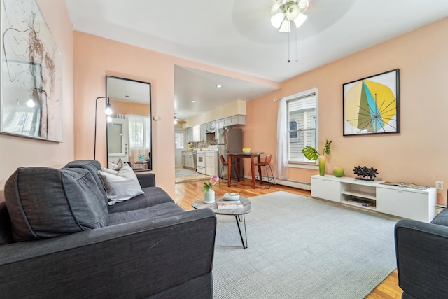 37 47th St, Weehawken, NJ 07086 - living area featuring light wood-style flooring, healthy amount of natural light, ceiling fan, and a baseboard heating unit