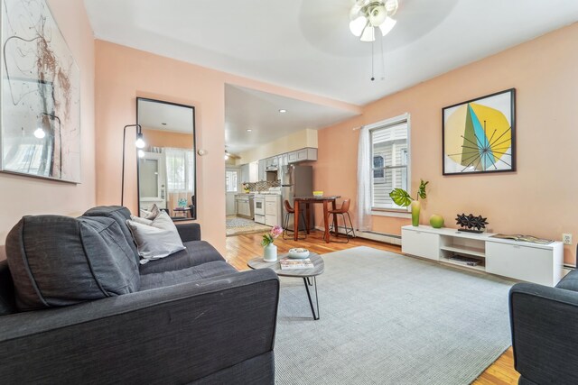 37 47th St, Weehawken, NJ 07086 - living area featuring light wood-style flooring, healthy amount of natural light, ceiling fan, and a baseboard heating unit