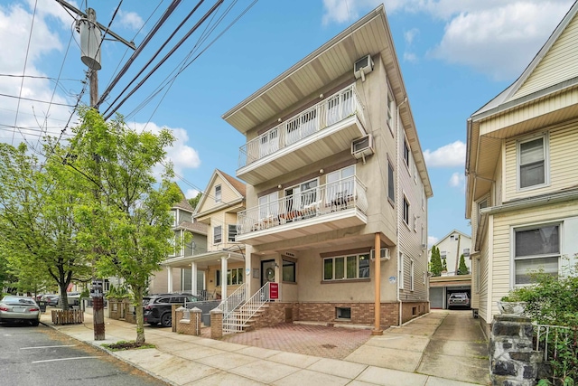 37 47th St, Weehawken, NJ 07086 - view of front of property featuring a balcony, a porch, a wall mounted air conditioner, crawl space, and stucco siding