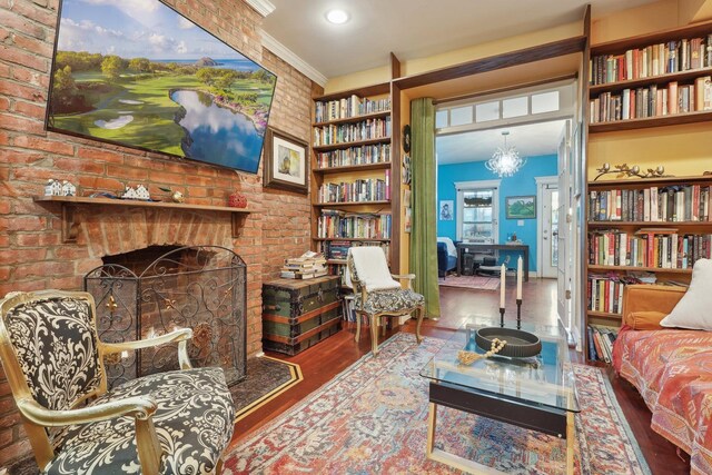 sitting room with hardwood / wood-style flooring, a chandelier, brick wall, built in features, and ornamental molding