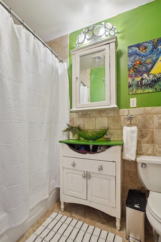 bathroom with toilet, tile patterned floors, tile walls, and vanity