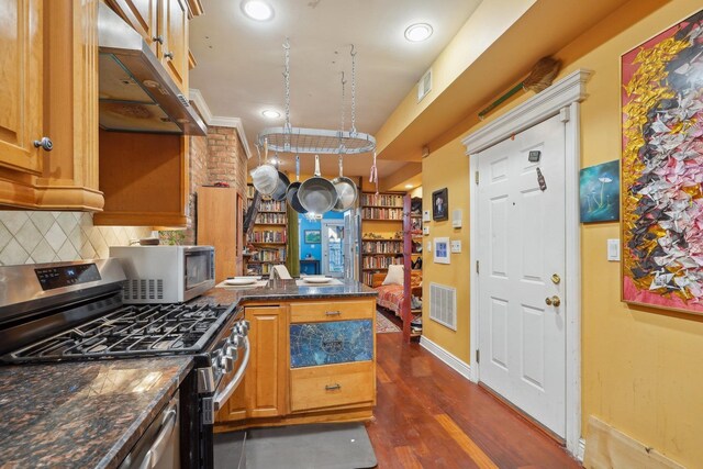 kitchen featuring dark stone countertops, decorative backsplash, dark hardwood / wood-style floors, and appliances with stainless steel finishes