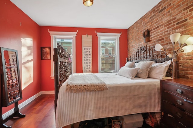 bedroom with brick wall and hardwood / wood-style flooring