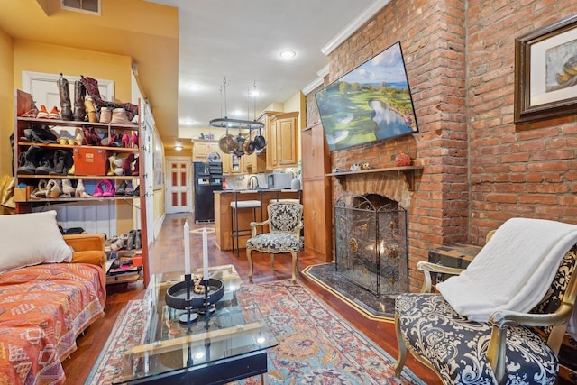 living room with ornamental molding, dark hardwood / wood-style flooring, and a brick fireplace