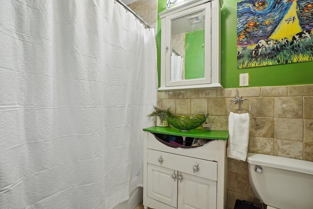 bathroom with toilet and tile walls