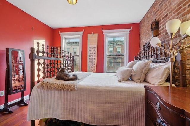 bedroom with brick wall and hardwood / wood-style flooring