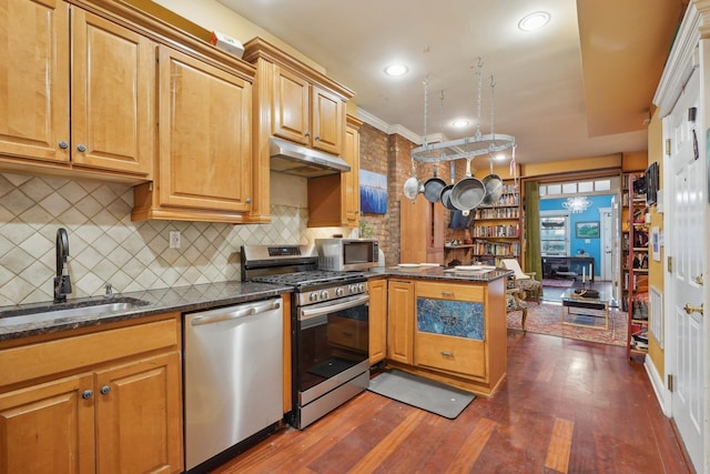 kitchen featuring stainless steel appliances, kitchen peninsula, dark hardwood / wood-style flooring, sink, and backsplash