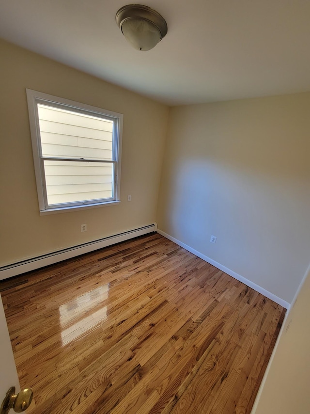 unfurnished room with wood finished floors, baseboards, and a baseboard radiator