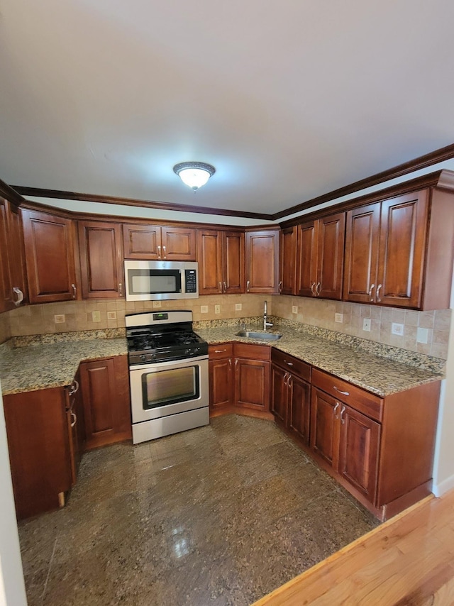 kitchen featuring backsplash, ornamental molding, stainless steel appliances, and a sink