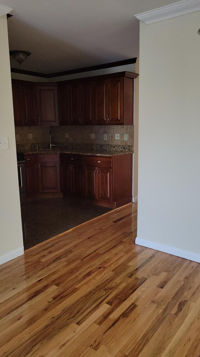 kitchen with a sink, baseboards, tasteful backsplash, and light wood-style floors