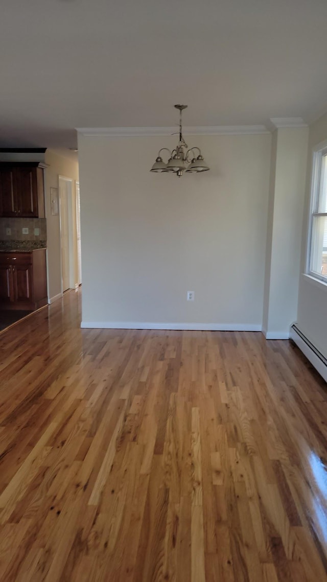 interior space with a notable chandelier, crown molding, baseboards, and wood finished floors