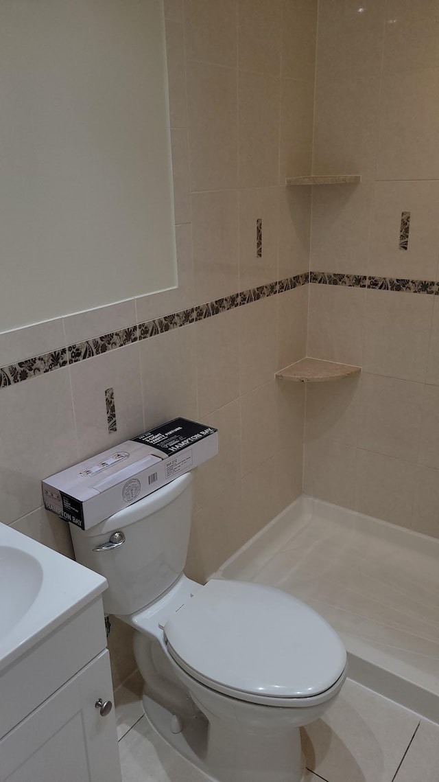 bathroom with tile walls, tile patterned floors, toilet, and vanity