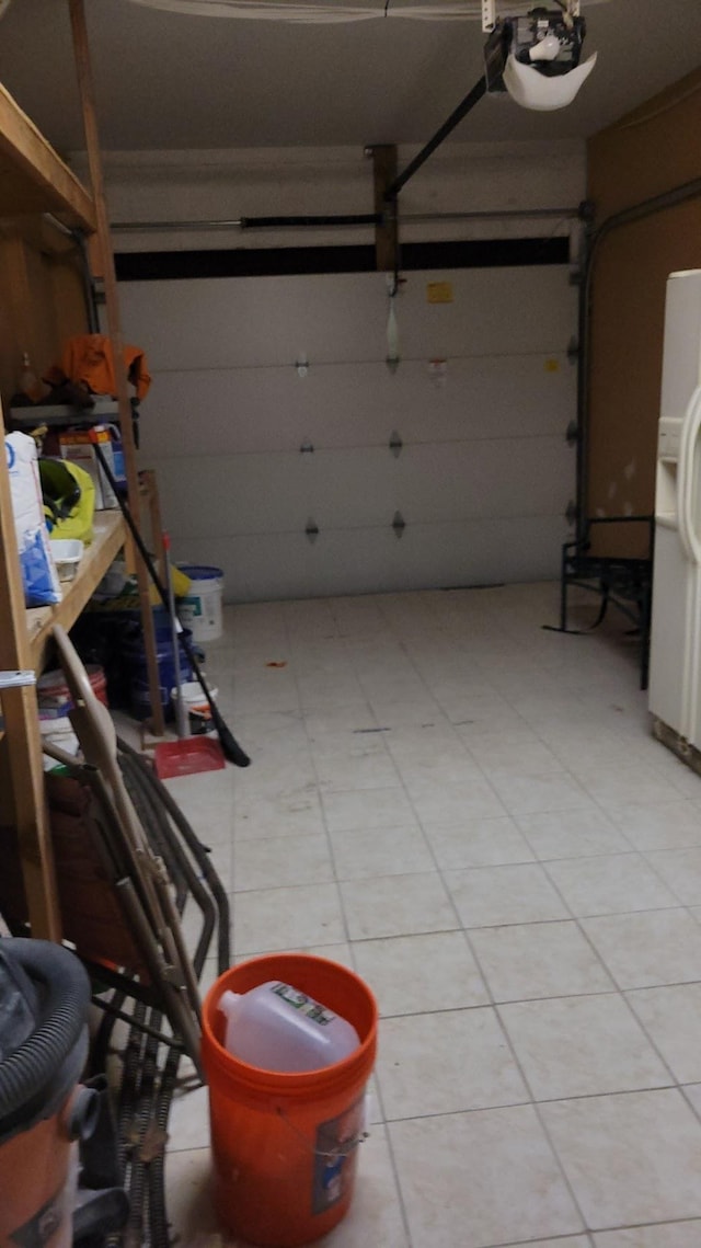 garage featuring white refrigerator with ice dispenser and a garage door opener