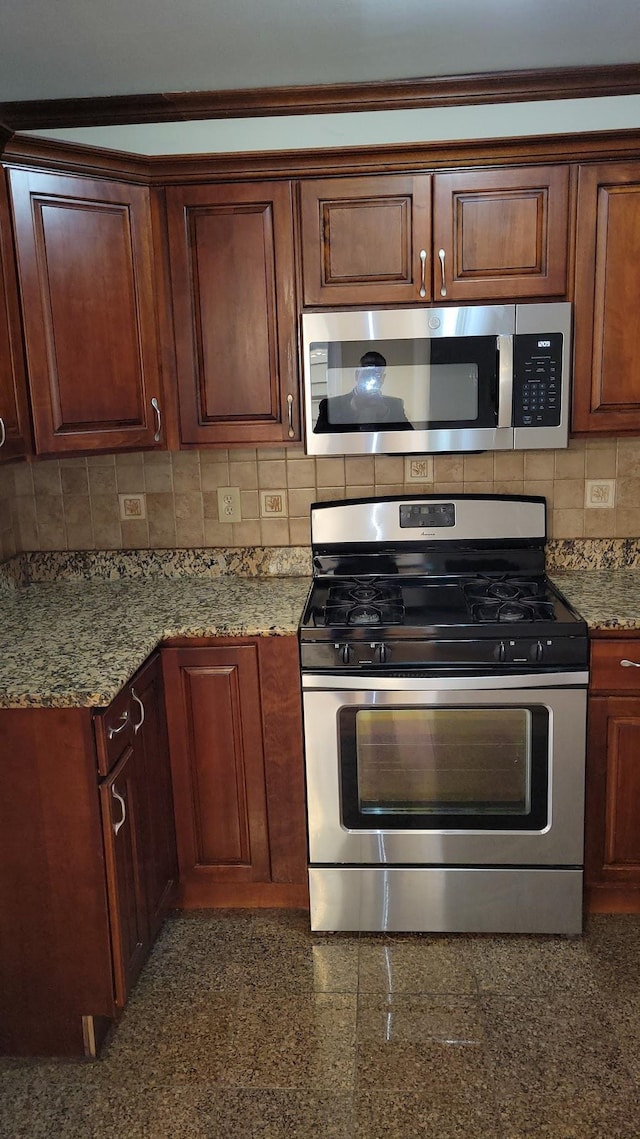 kitchen featuring granite finish floor, stone counters, stainless steel appliances, and tasteful backsplash