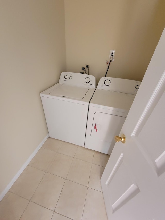 laundry room featuring washing machine and clothes dryer, laundry area, baseboards, and light tile patterned floors